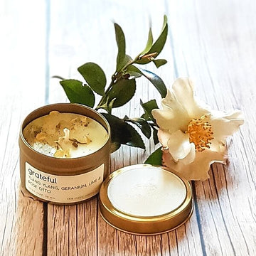 Lemon Canary Grateful Organic Essential Oil Candle on a table with white Gardenia flower